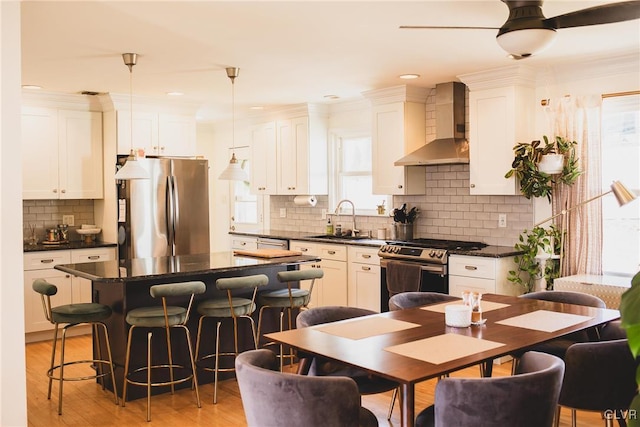 kitchen with dark countertops, appliances with stainless steel finishes, and wall chimney exhaust hood