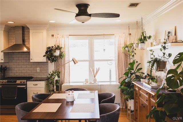 dining area featuring ceiling fan, visible vents, wood finished floors, and crown molding