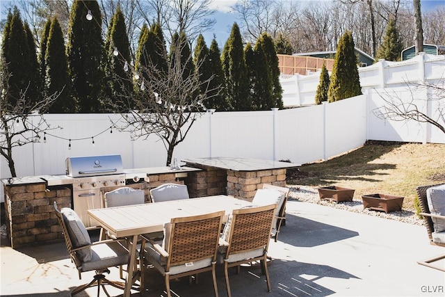 view of patio with outdoor dining area, an outdoor kitchen, a fenced backyard, and grilling area