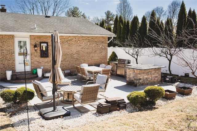 view of patio / terrace featuring outdoor dining area, a grill, an outdoor kitchen, and fence