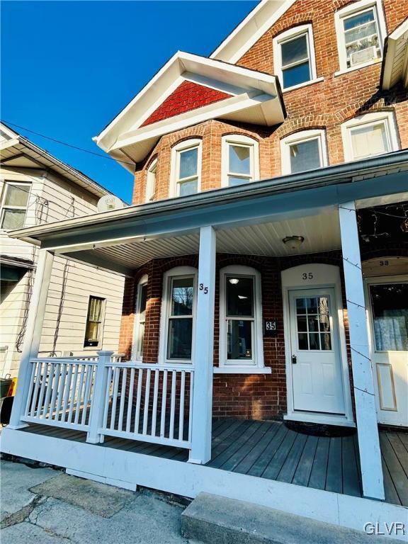 doorway to property with brick siding and covered porch