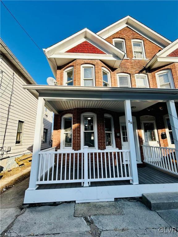 townhome / multi-family property with brick siding and a porch