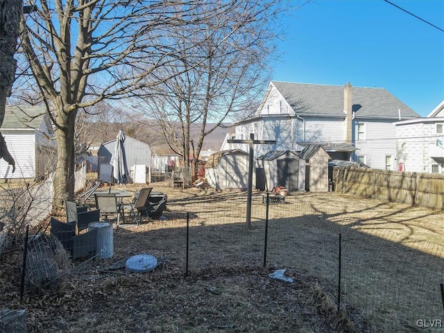 view of yard featuring a storage shed, an outdoor structure, and fence