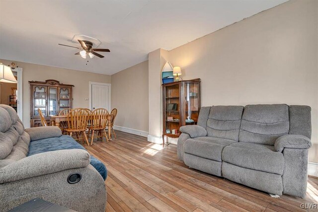 living area featuring a ceiling fan, light wood-type flooring, and baseboards