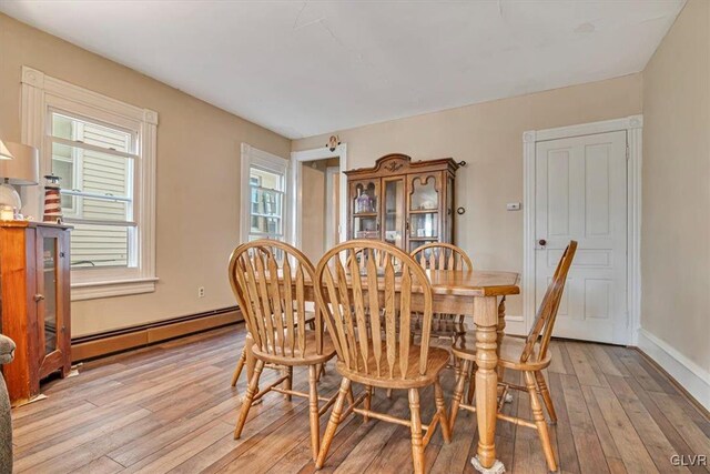 dining space featuring light wood-style floors, baseboards, and baseboard heating