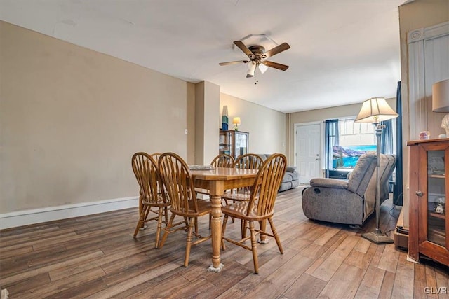 dining space with baseboards, a ceiling fan, and wood finished floors