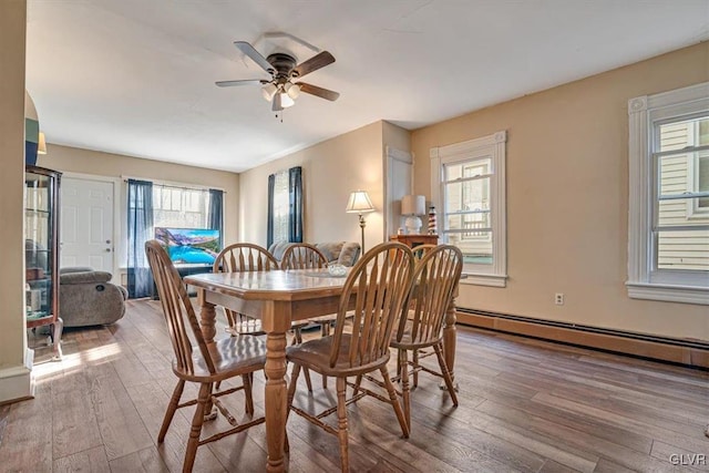 dining area with hardwood / wood-style flooring, a wealth of natural light, and a baseboard radiator