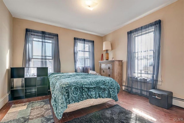 bedroom with wood finished floors, baseboards, and baseboard heating