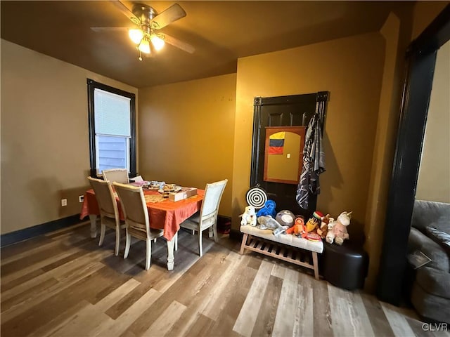 dining space with baseboards, wood finished floors, and a ceiling fan