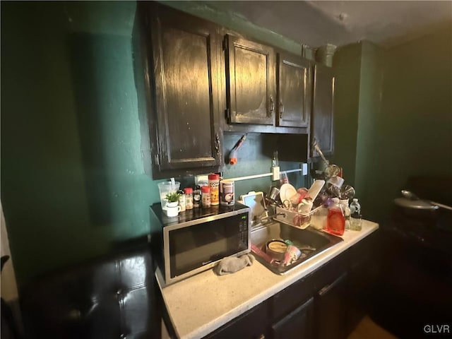 kitchen featuring a sink, dark brown cabinetry, and light countertops