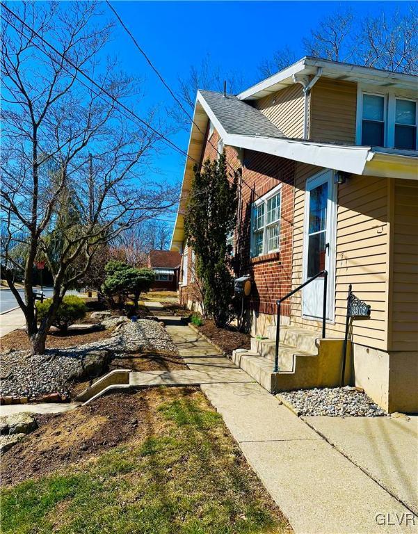 view of side of property with brick siding and roof with shingles