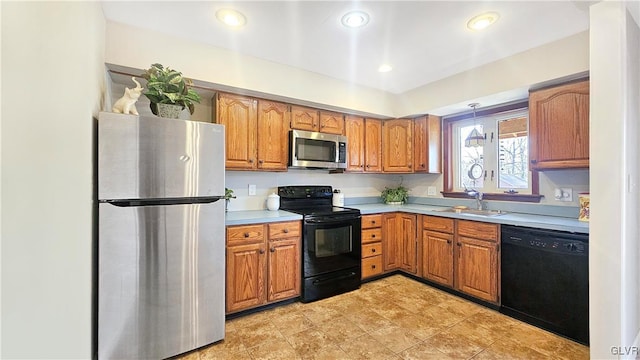 kitchen featuring decorative light fixtures, light countertops, brown cabinets, black appliances, and a sink