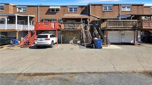 multi unit property with stairs, an attached garage, and brick siding