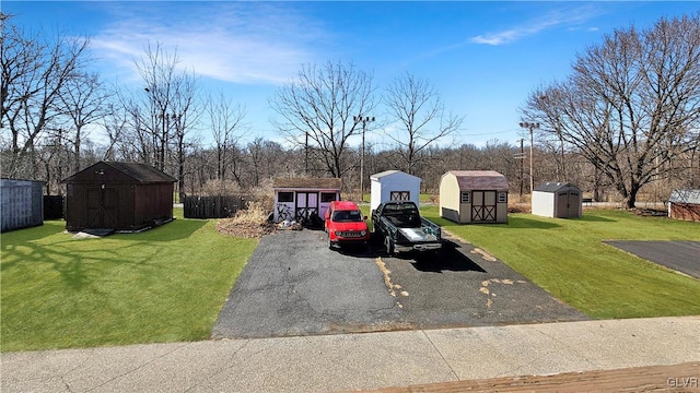 view of front facade featuring a storage shed, fence, an outbuilding, and a front lawn