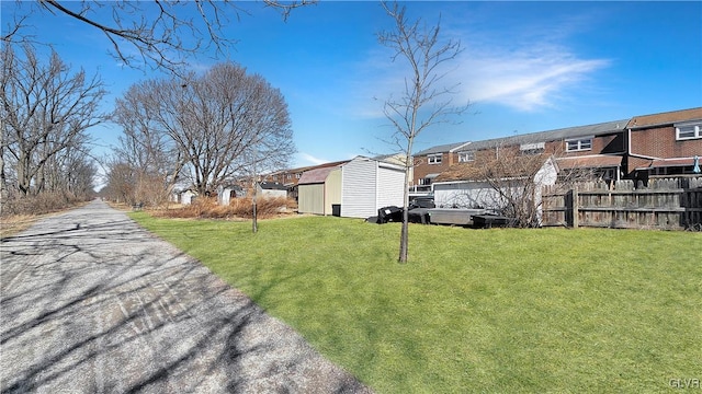 view of yard featuring an outbuilding, a storage unit, fence, and a residential view