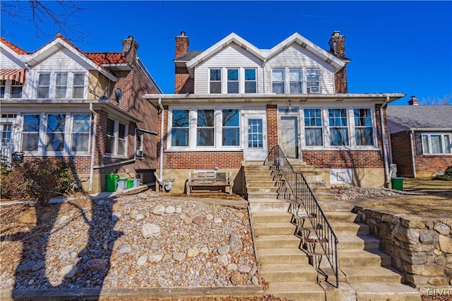 view of front of house with brick siding, entry steps, and a chimney