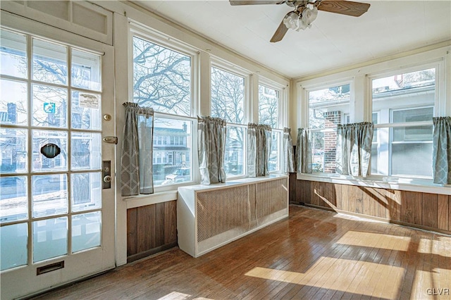 unfurnished sunroom with a wealth of natural light, radiator, and ceiling fan