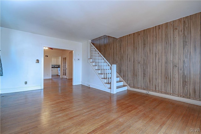 interior space with wood walls, stairs, baseboards, and wood-type flooring