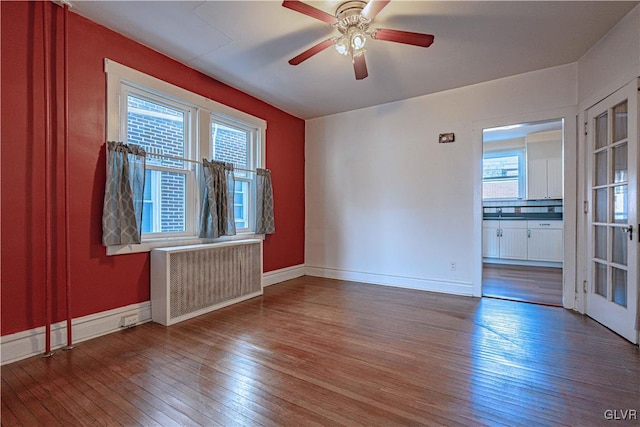 unfurnished room featuring radiator, plenty of natural light, and wood-type flooring