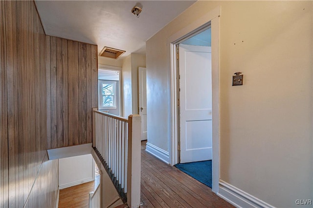 corridor with an upstairs landing, attic access, baseboards, and hardwood / wood-style floors