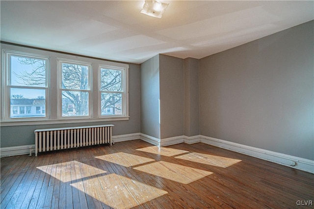 empty room with radiator, baseboards, and wood-type flooring