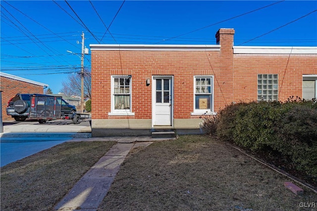 rear view of house featuring brick siding and a chimney