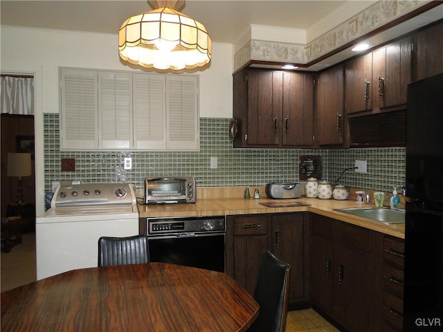 kitchen featuring a toaster, washer / clothes dryer, freestanding refrigerator, and dark brown cabinetry