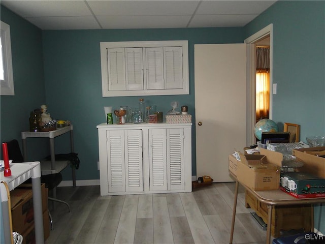 interior space featuring baseboards, a paneled ceiling, and light wood-style floors