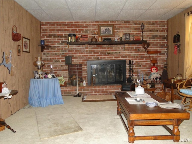 living room with wooden walls, carpet flooring, and a fireplace