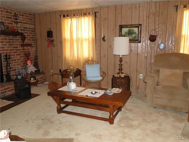 living area with a drop ceiling, carpet, a fireplace, and wooden walls