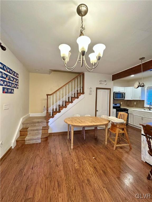 dining room featuring dark wood-style floors, baseboards, stairs, and an inviting chandelier