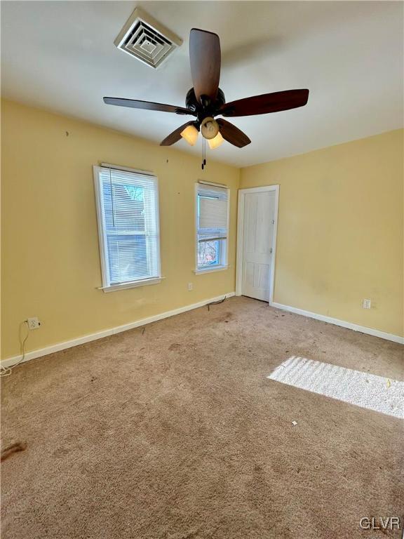 empty room with visible vents, baseboards, carpet, and ceiling fan