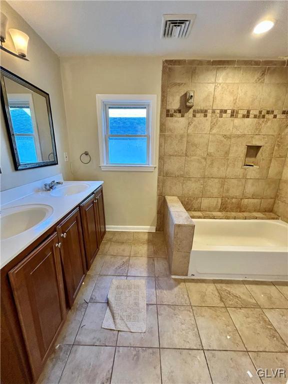 bathroom with double vanity, visible vents, baseboards, and a sink