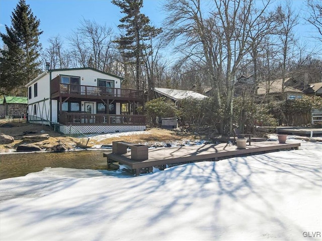 snow covered back of property with a deck