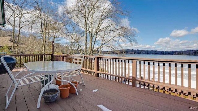 deck with a water view and outdoor dining space