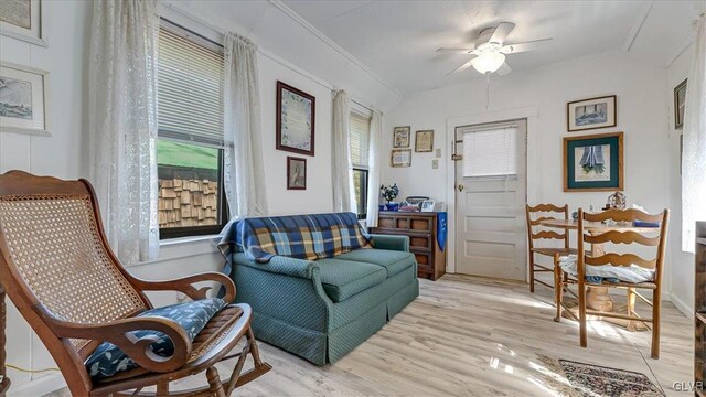 sitting room with a ceiling fan, crown molding, and light wood finished floors