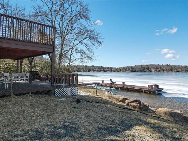 view of dock with a wooded view and a deck with water view