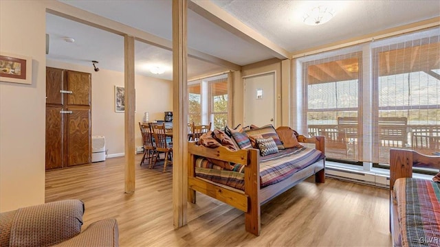 living room with beamed ceiling, light wood-style floors, and baseboard heating