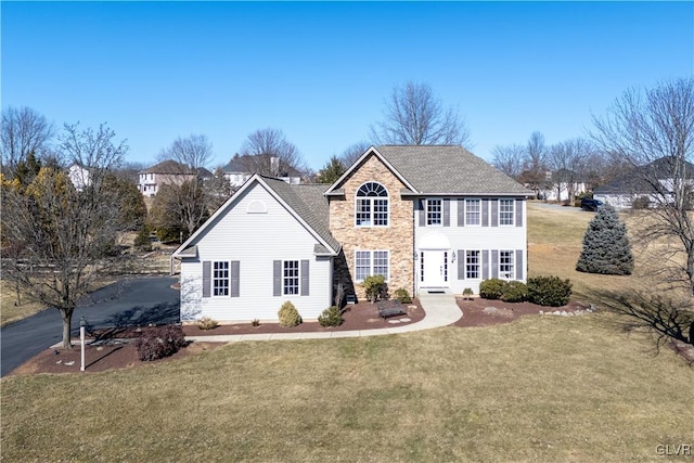 colonial inspired home with a front yard and stone siding