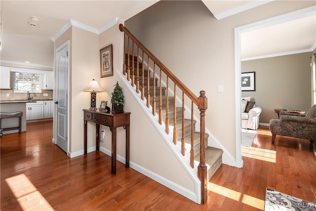 stairway with crown molding, hardwood / wood-style flooring, and baseboards