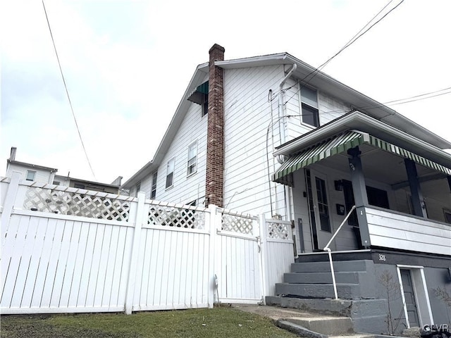 view of home's exterior with a chimney and fence