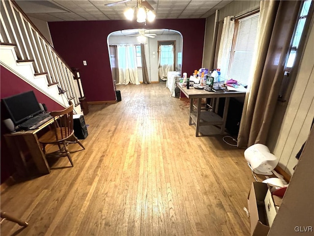 dining area with a drop ceiling, light wood-type flooring, arched walkways, and stairs