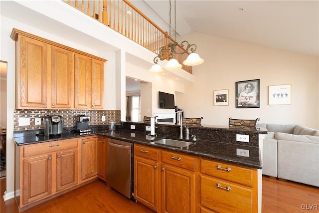 kitchen featuring stainless steel dishwasher, a sink, high vaulted ceiling, and open floor plan