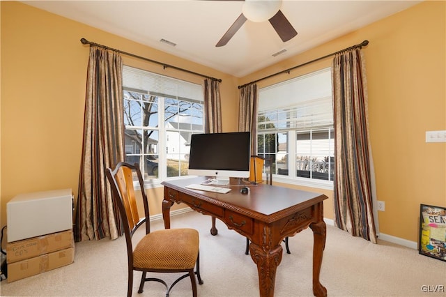 office space with a wealth of natural light, visible vents, light colored carpet, and a ceiling fan