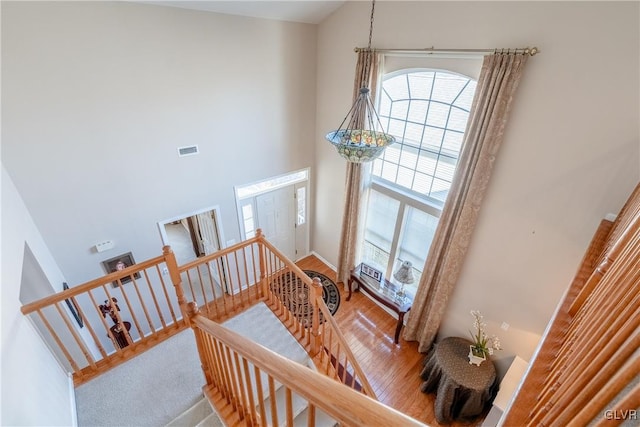 stairs with baseboards, visible vents, wood finished floors, and a high ceiling