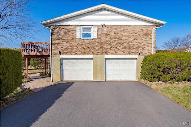 view of property exterior featuring aphalt driveway, brick siding, and an attached garage