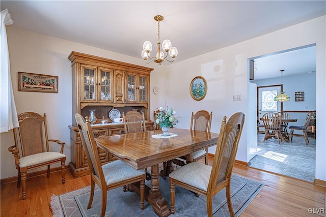 dining area with a notable chandelier, baseboards, and light wood finished floors