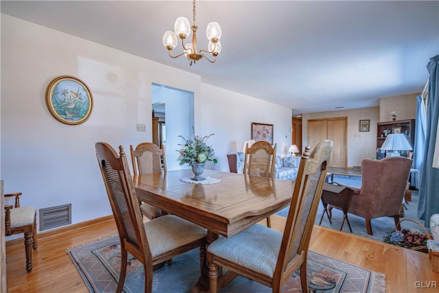 dining space featuring a notable chandelier, light wood-style floors, and visible vents