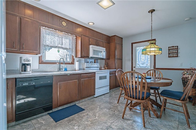 kitchen featuring a sink, white appliances, pendant lighting, and light countertops