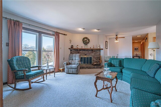 living area with a brick fireplace, a ceiling fan, and carpet